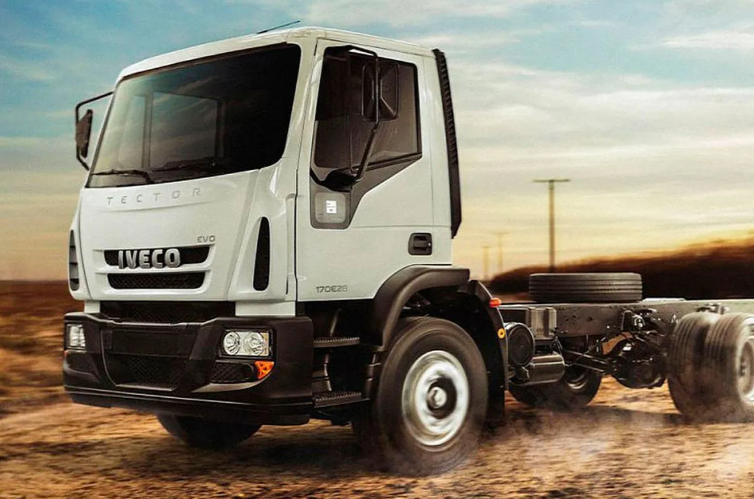 Chasis de camión Iveco blanco circulando por un camino polvoriento al atardecer.