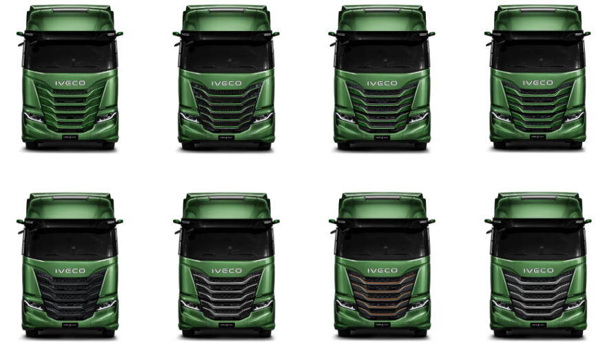 Un camión semirremolque Iveco verde circula por una carretera soleada con montañas y árboles al fondo.