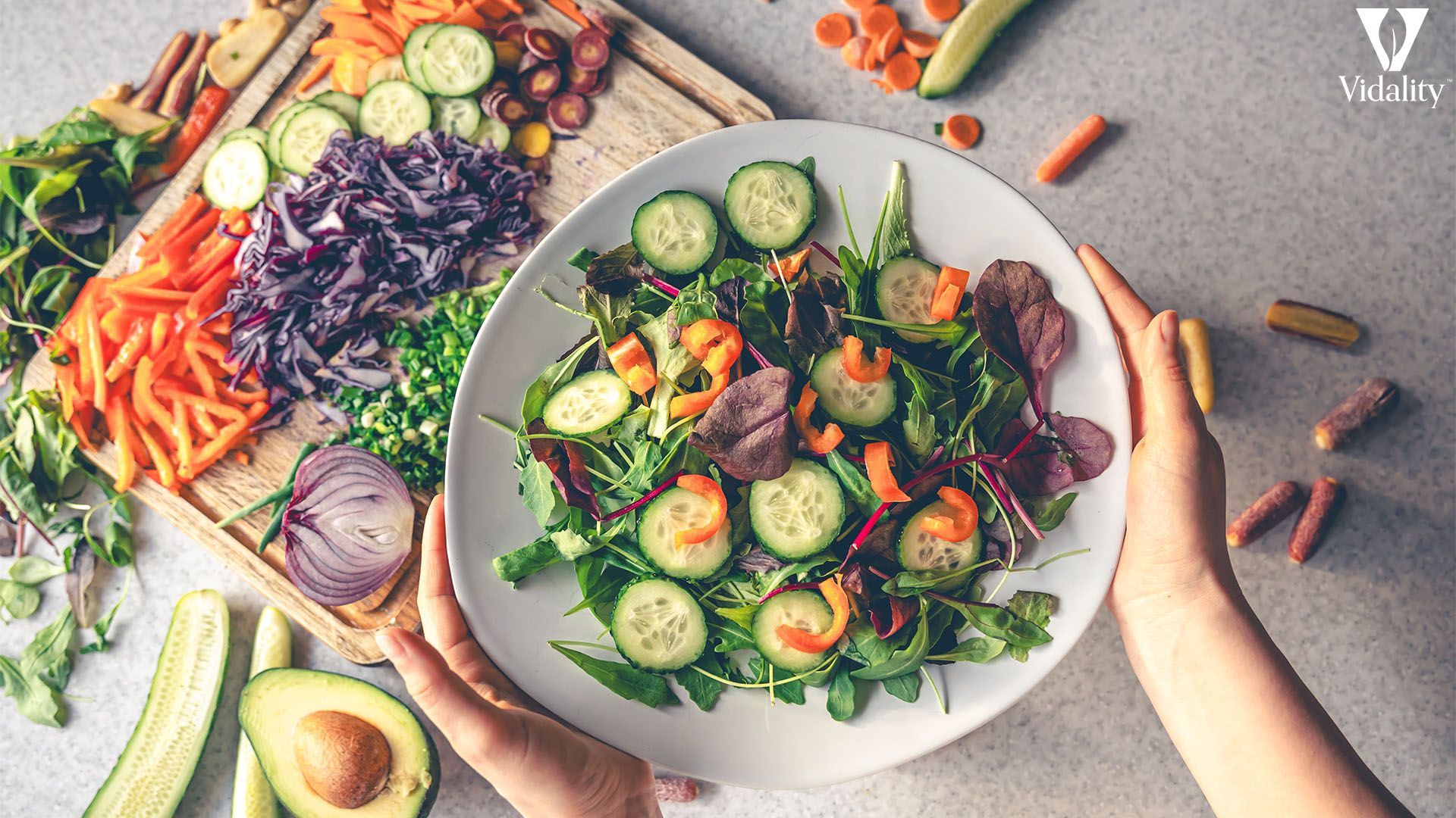 A person holding a plate of colorful vegetables and salad, showcasing a healthy and nutritious meal.