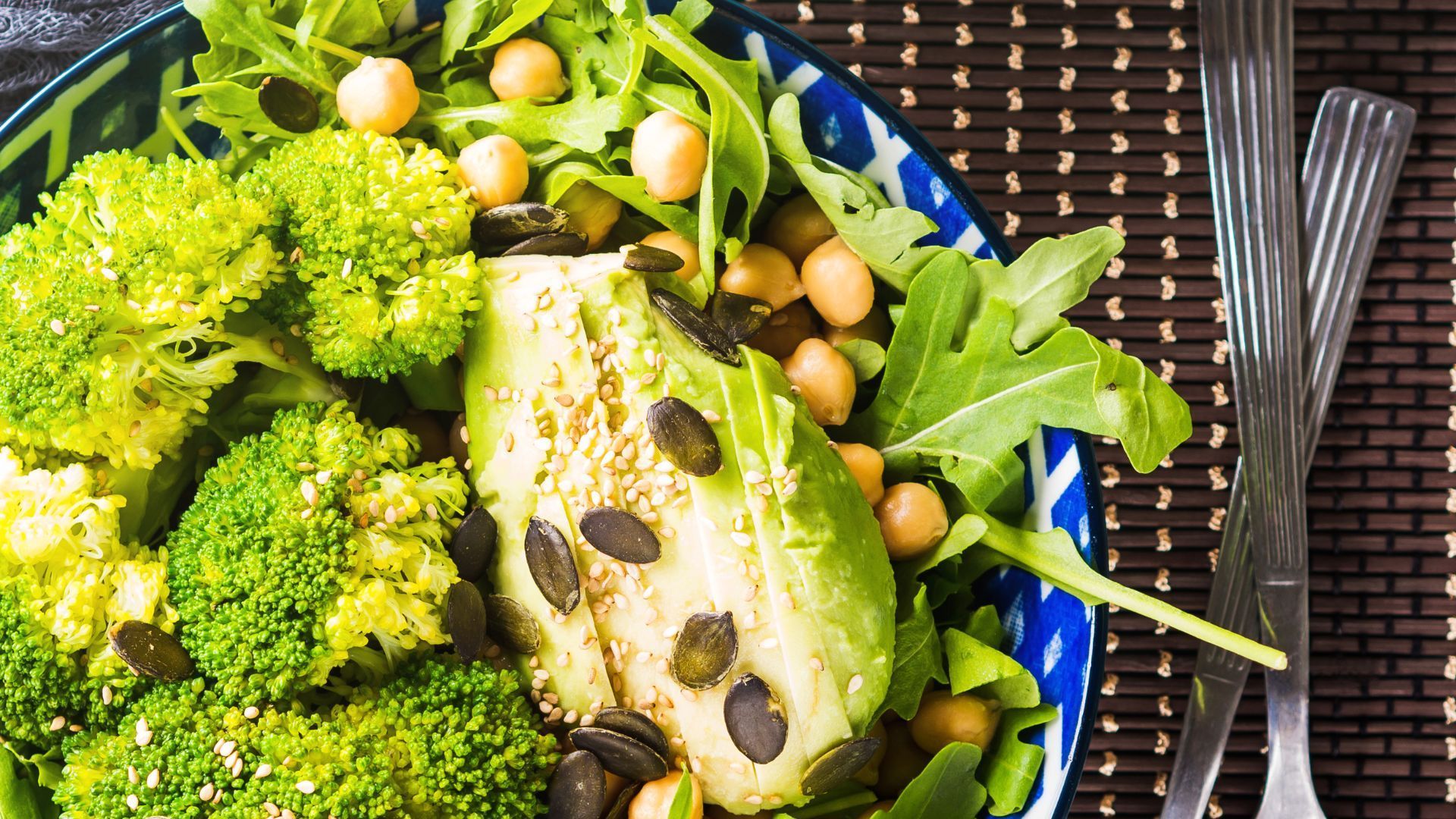 A bowl of broccoli and beans on a wooden table.