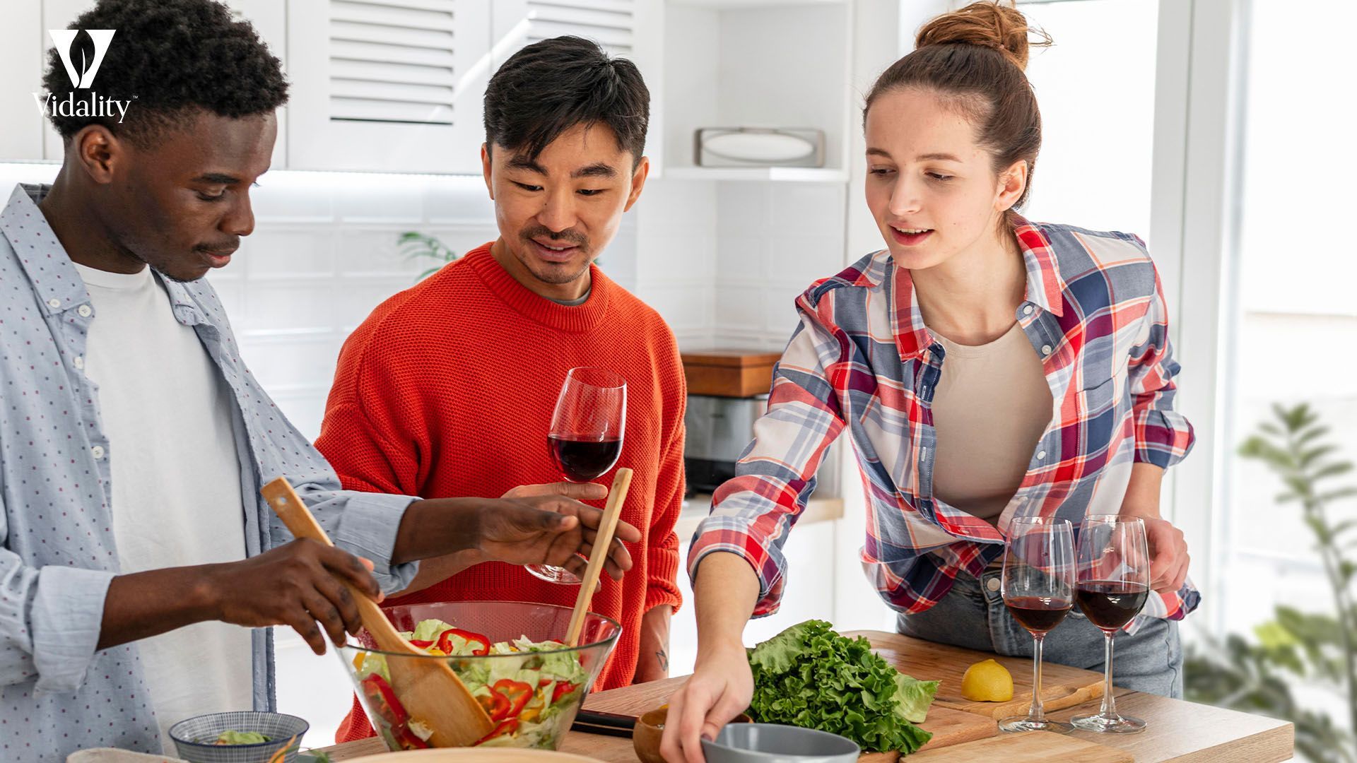 Three individuals cooking together in a kitchen, chopping vegetables and stirring pots on the stove.