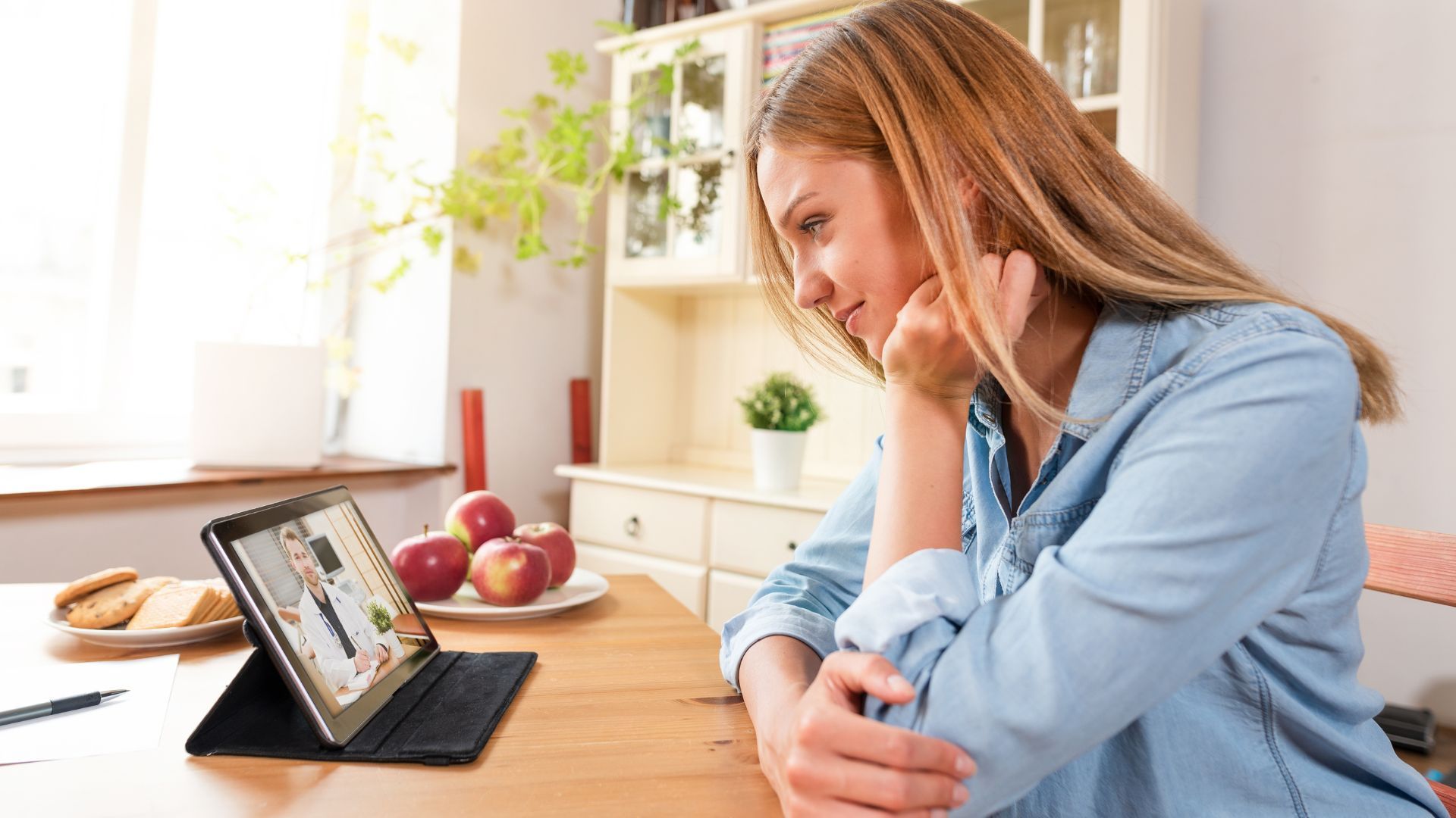 A woman sitting at a table with a laptop and a cup of coffee, working on her computer.
