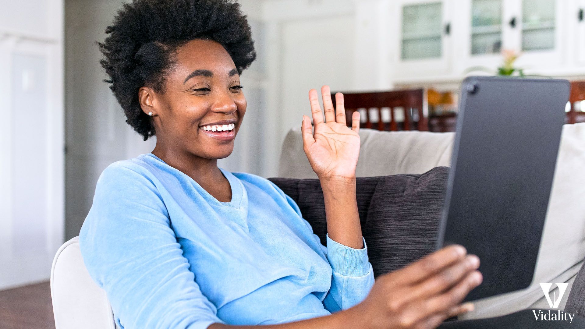 A woman sitting on a couch, holding a tablet.