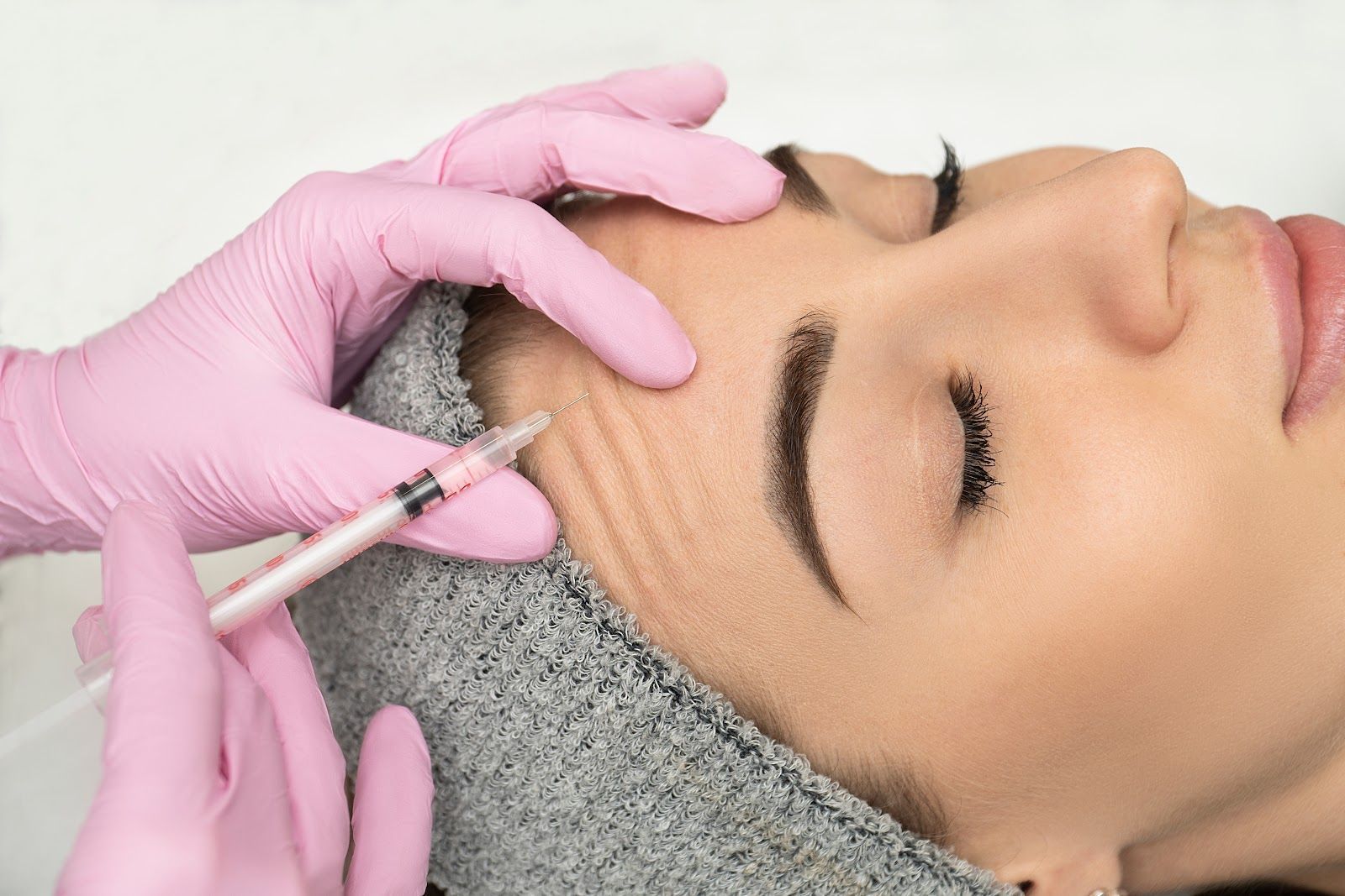 Cosmetic treatment on a woman’s face with a syringe near her temple