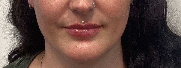 Close-up of a woman’s lower face with dark hair, a nose ring, and a neutral expression