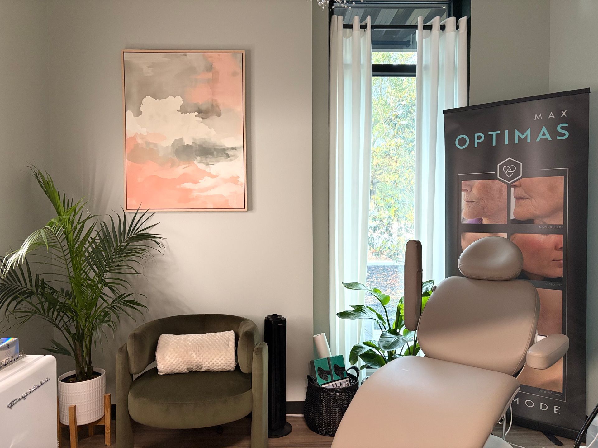 Modern clinic room with treatment chair, armchair, plants, and an OPTIMAS poster by the window