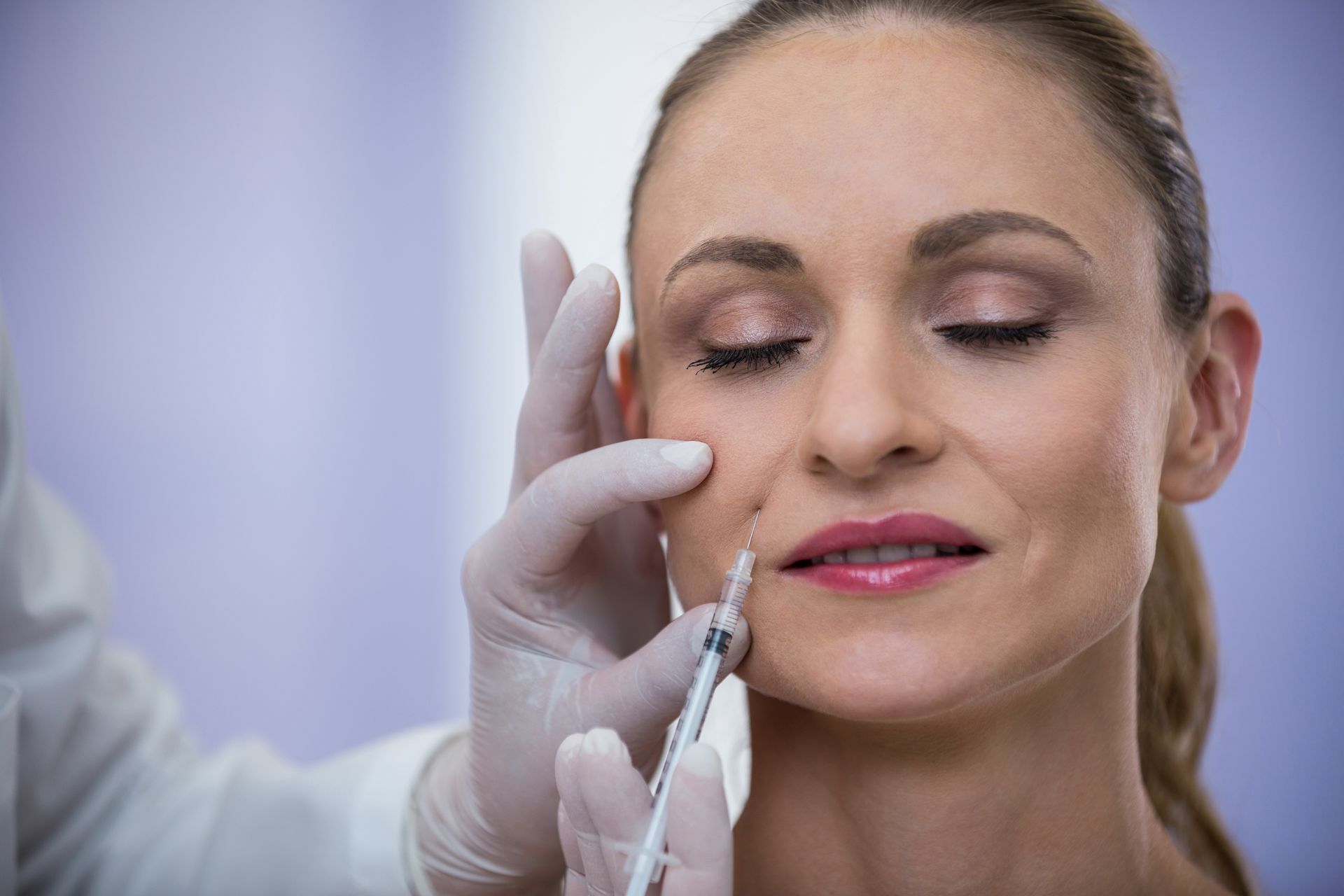 Person receiving facial injection in a medical setting.