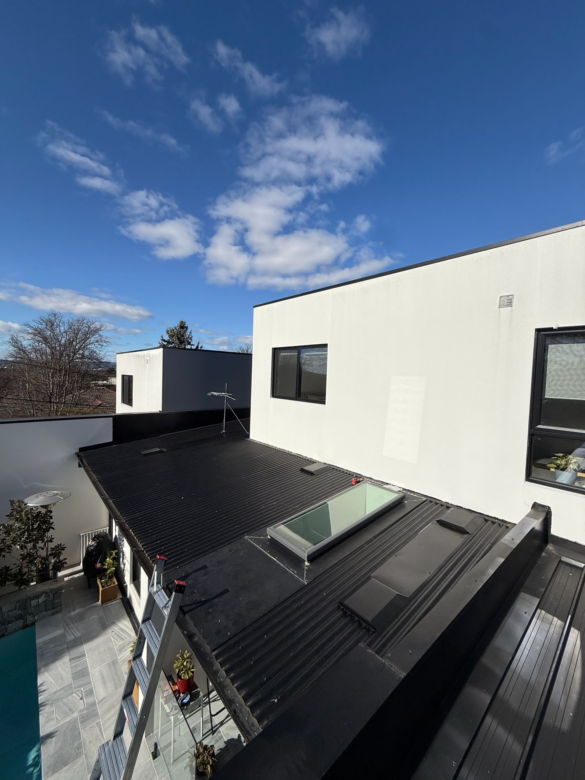 Black roof with skylight and white building against a blue sky— Vent Wise in Twin Waters, QLD.