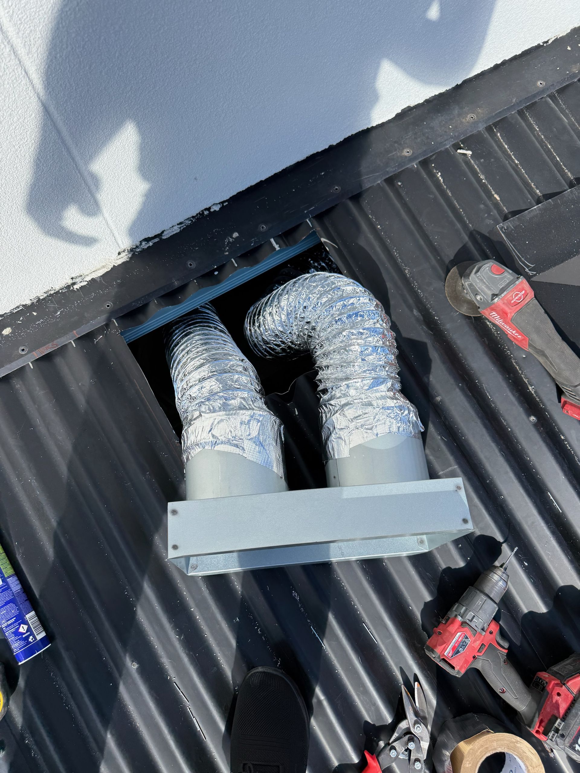 Ventilation ducts on a corrugated roof, with tools nearby.— Vent Wise in Twin Waters, QLD