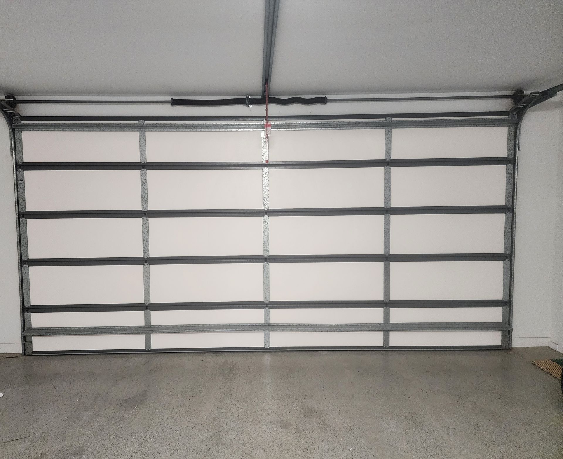 An empty garage with two garage doors open and a concrete floor. — Vent Wise in Canberra, ACT