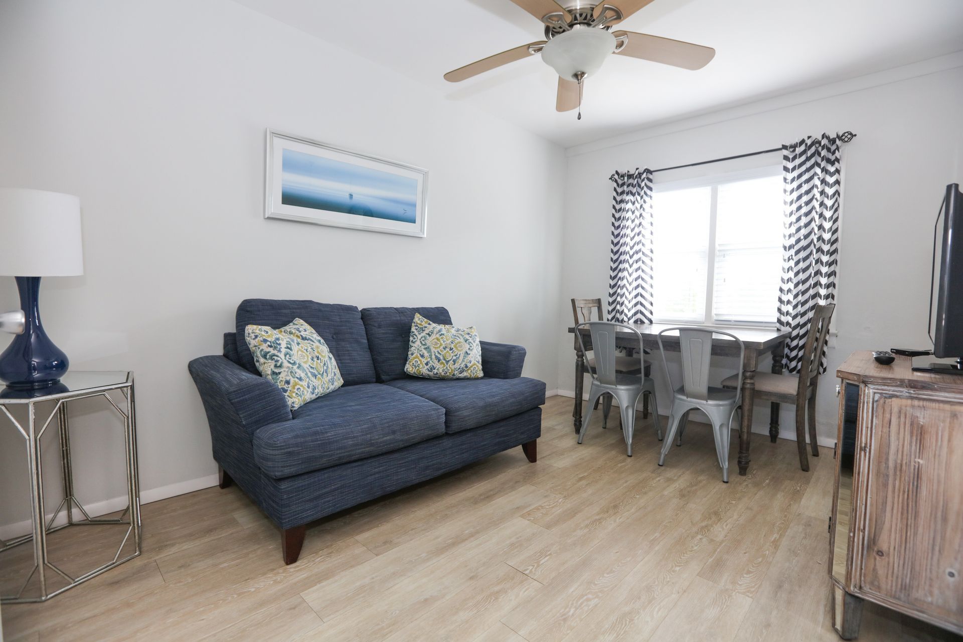 A living room with a blue couch and a ceiling fan