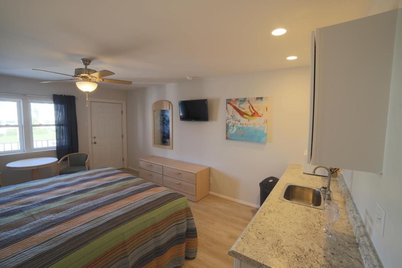 A bedroom with a bed , sink , television and ceiling fan.