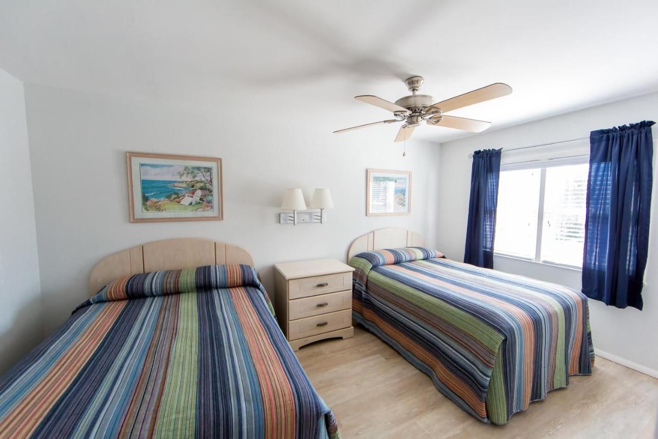 A bedroom with two beds and a ceiling fan
