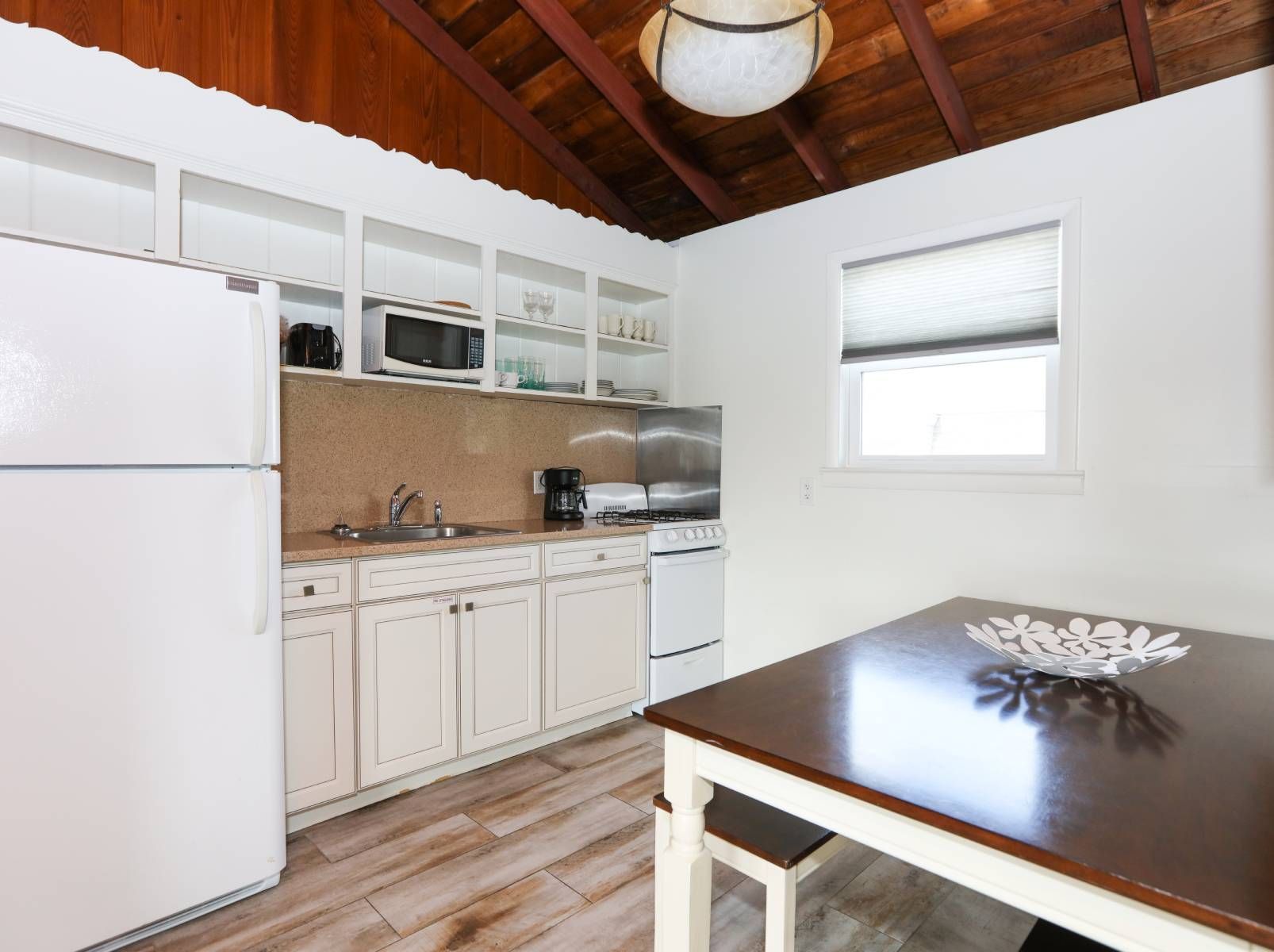 A kitchen with a table , refrigerator , sink and microwave.
