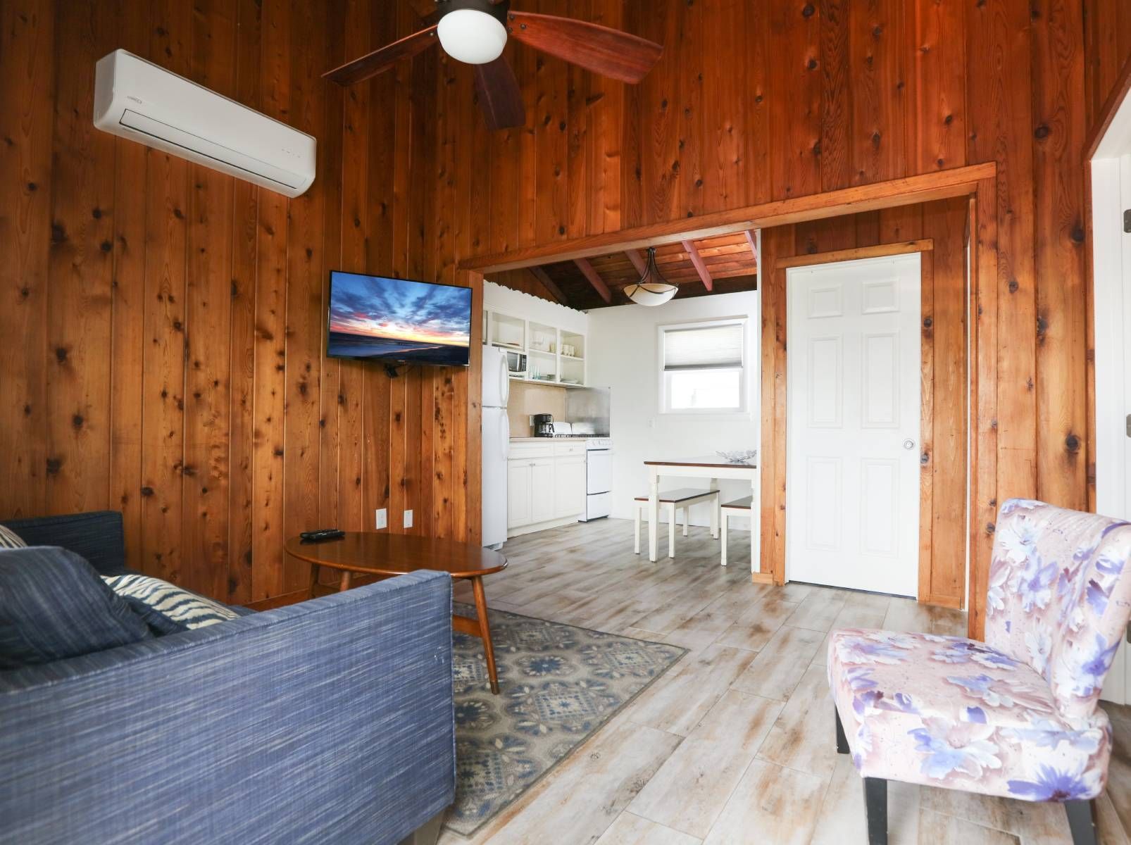 A living room with a couch , chair , television and ceiling fan.