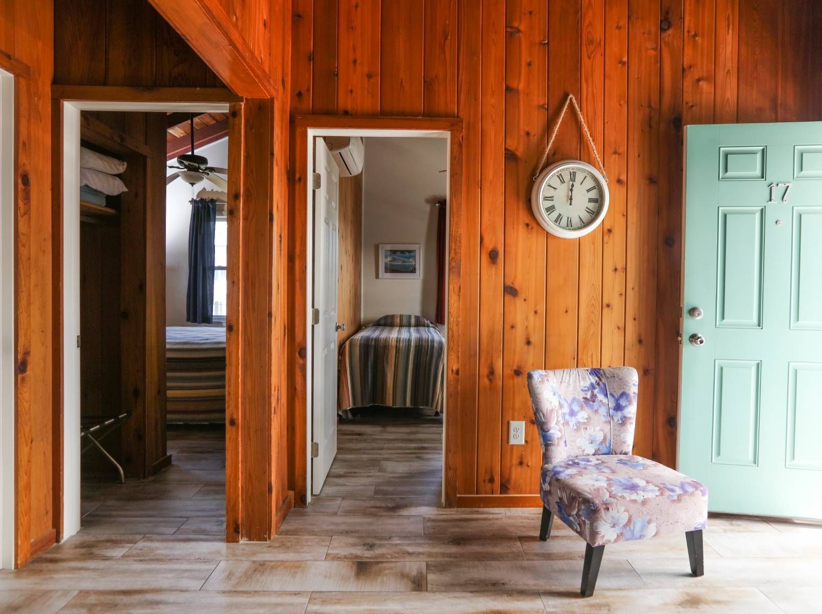 A room with wood paneling , a chair and a clock on the wall.