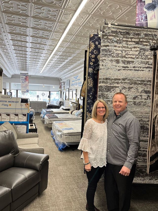 A man and a woman are standing in a furniture store.