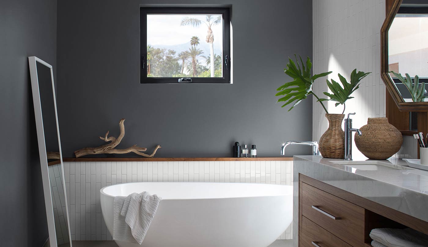 A bathroom with a bathtub , sink , mirror and window.