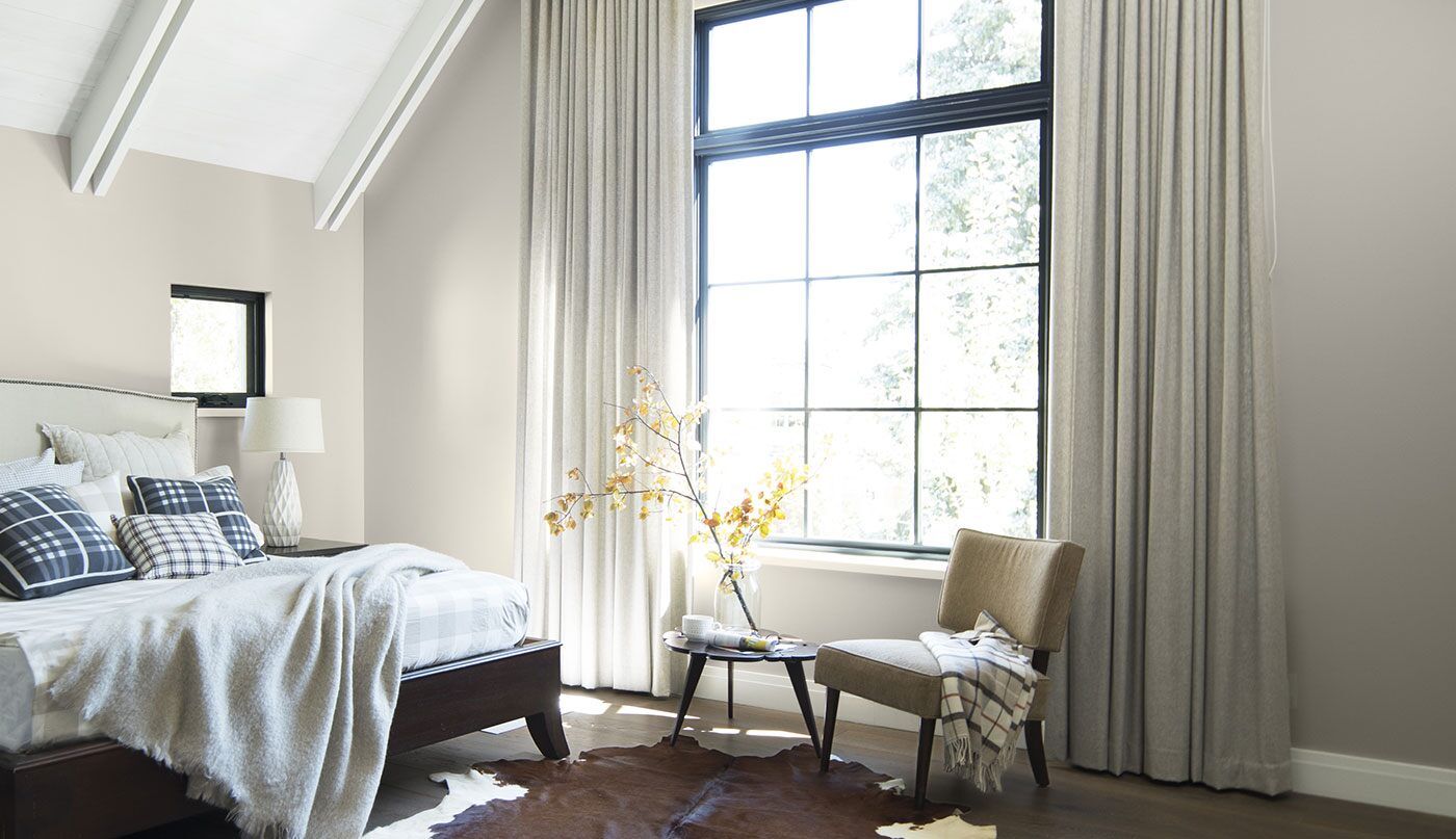 A bedroom with a bed , chair , table and window.