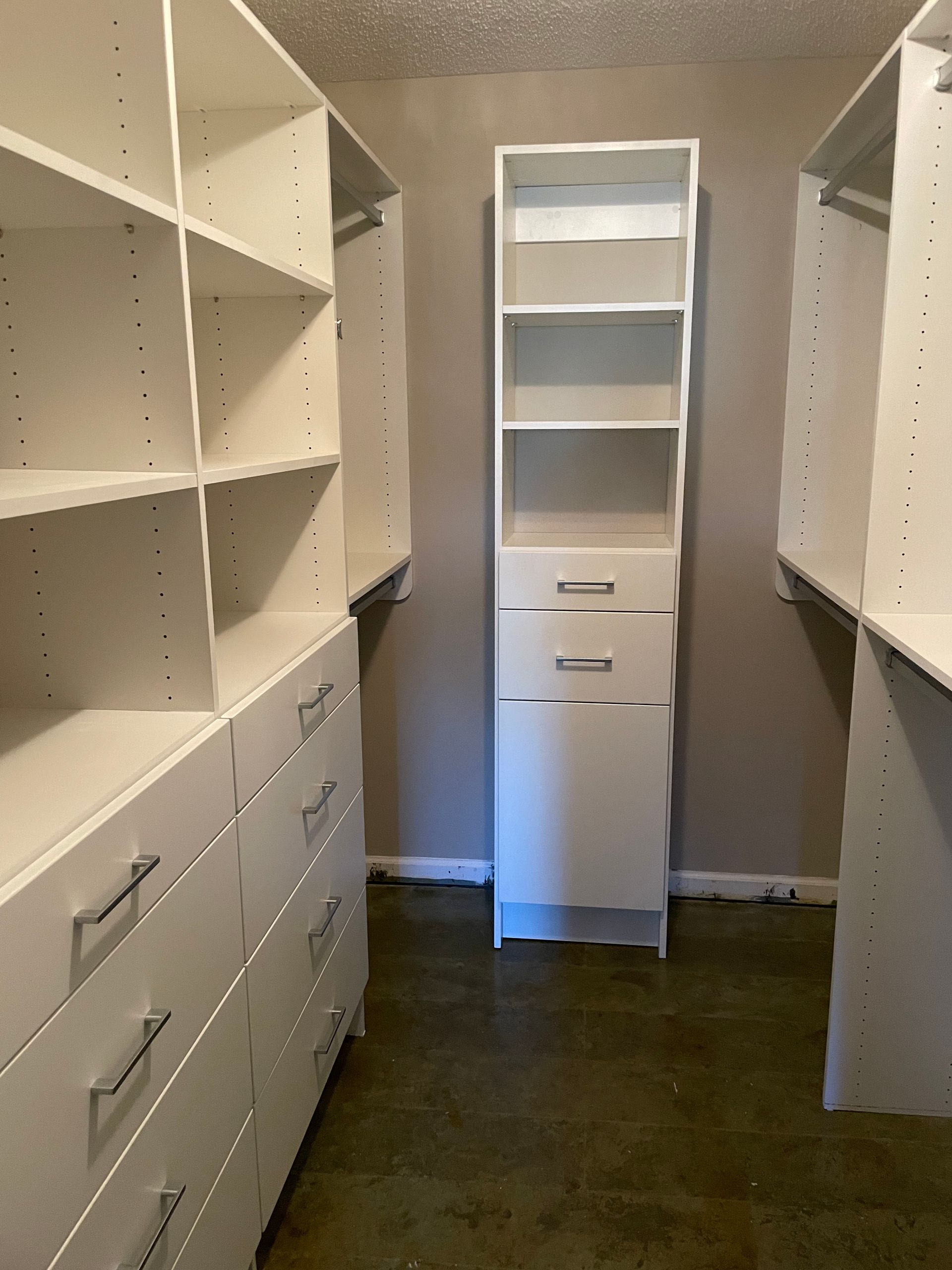 White closet shelving system in a room with a central shelving unit.