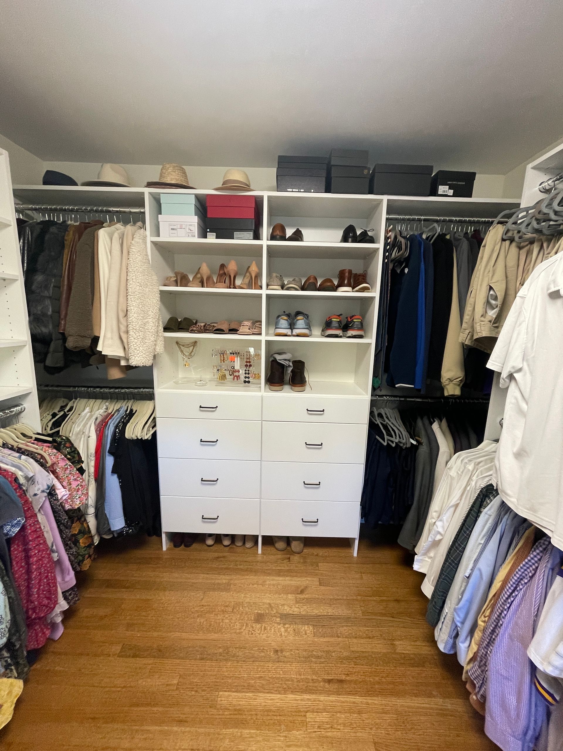 White walk-in closet with clothes racks, drawers, and shoe shelves. Hardwood floor. Neutral tones.