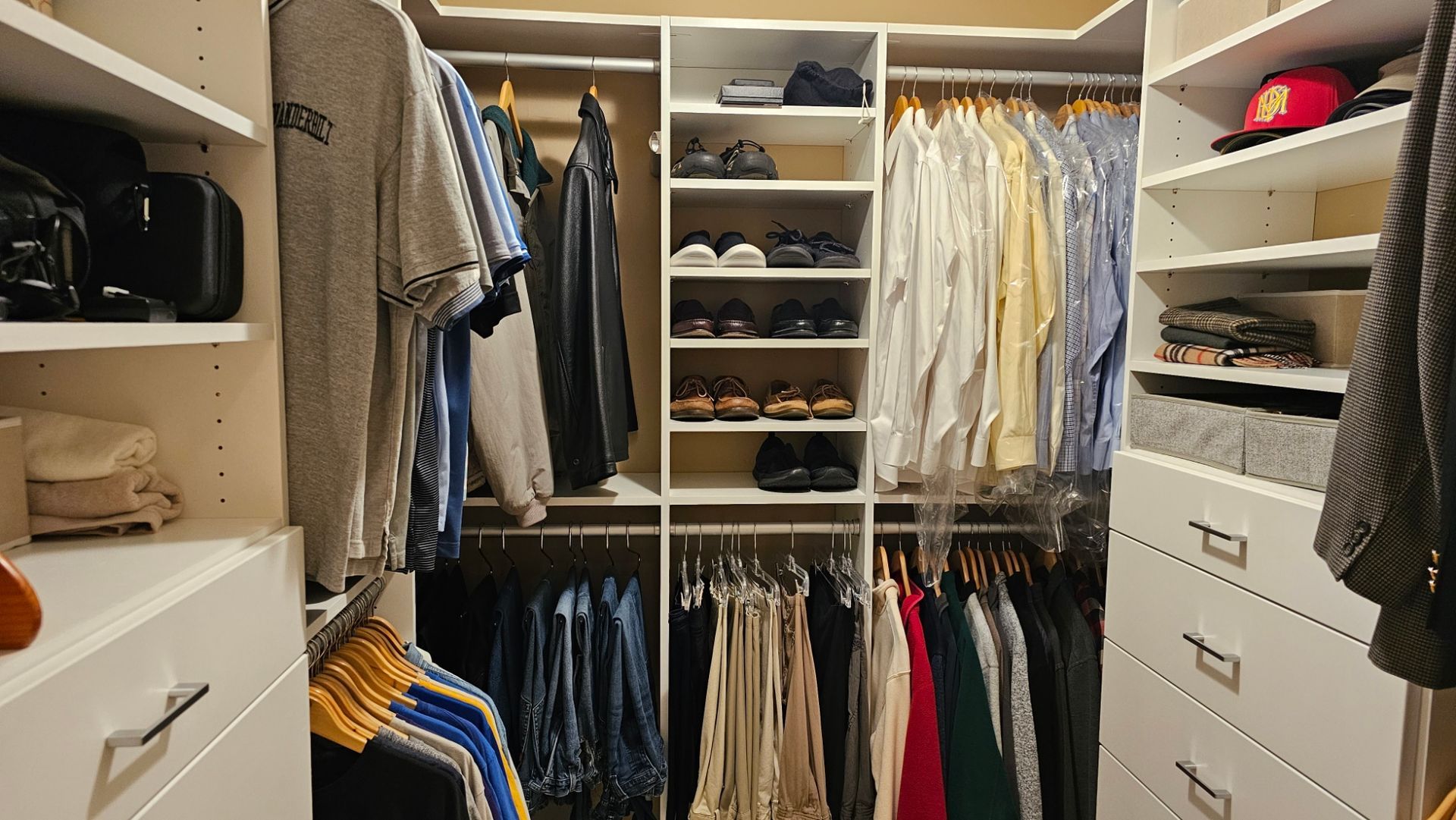 Walk-in closet with organized clothing on shelves and hanging rods; neutral color scheme.