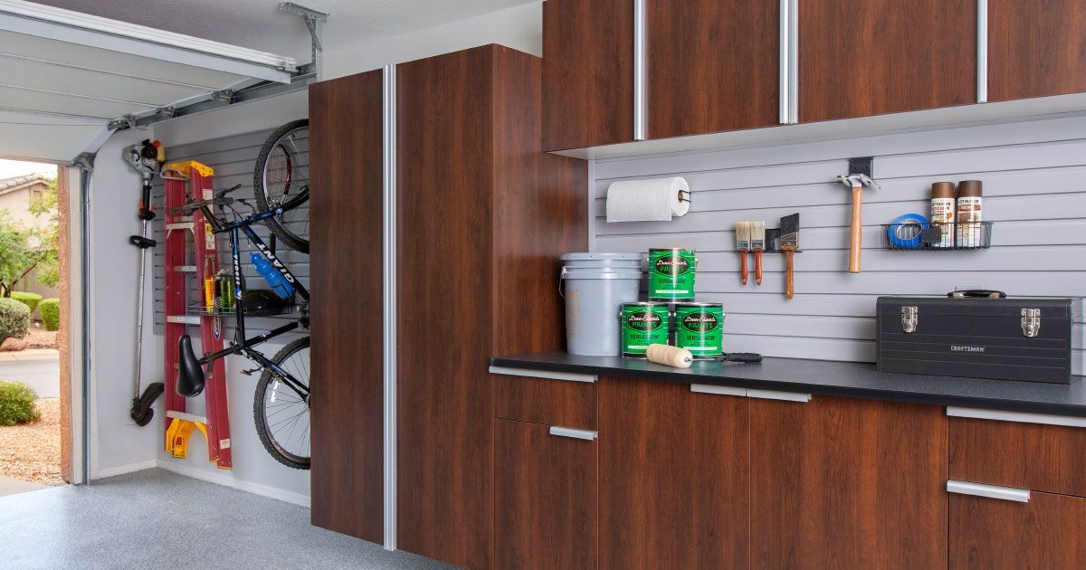 Garage with wood cabinets, wall shelves, hanging tools, and bikes stored inside.