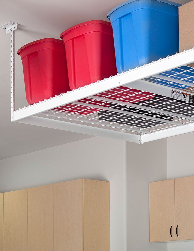 Red, pink, and blue storage bins on a white shelf above kitchen cabinets