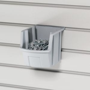 A bin filled with screws is hanging on a wall.
