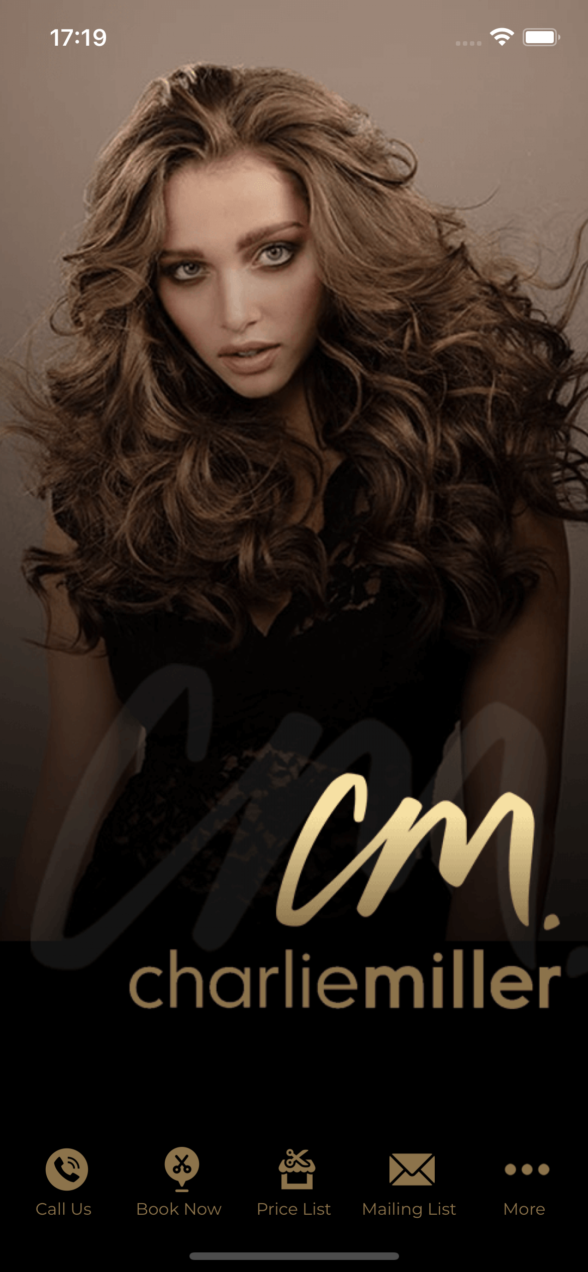 Woman with voluminous brown hair, dark top. Gold 