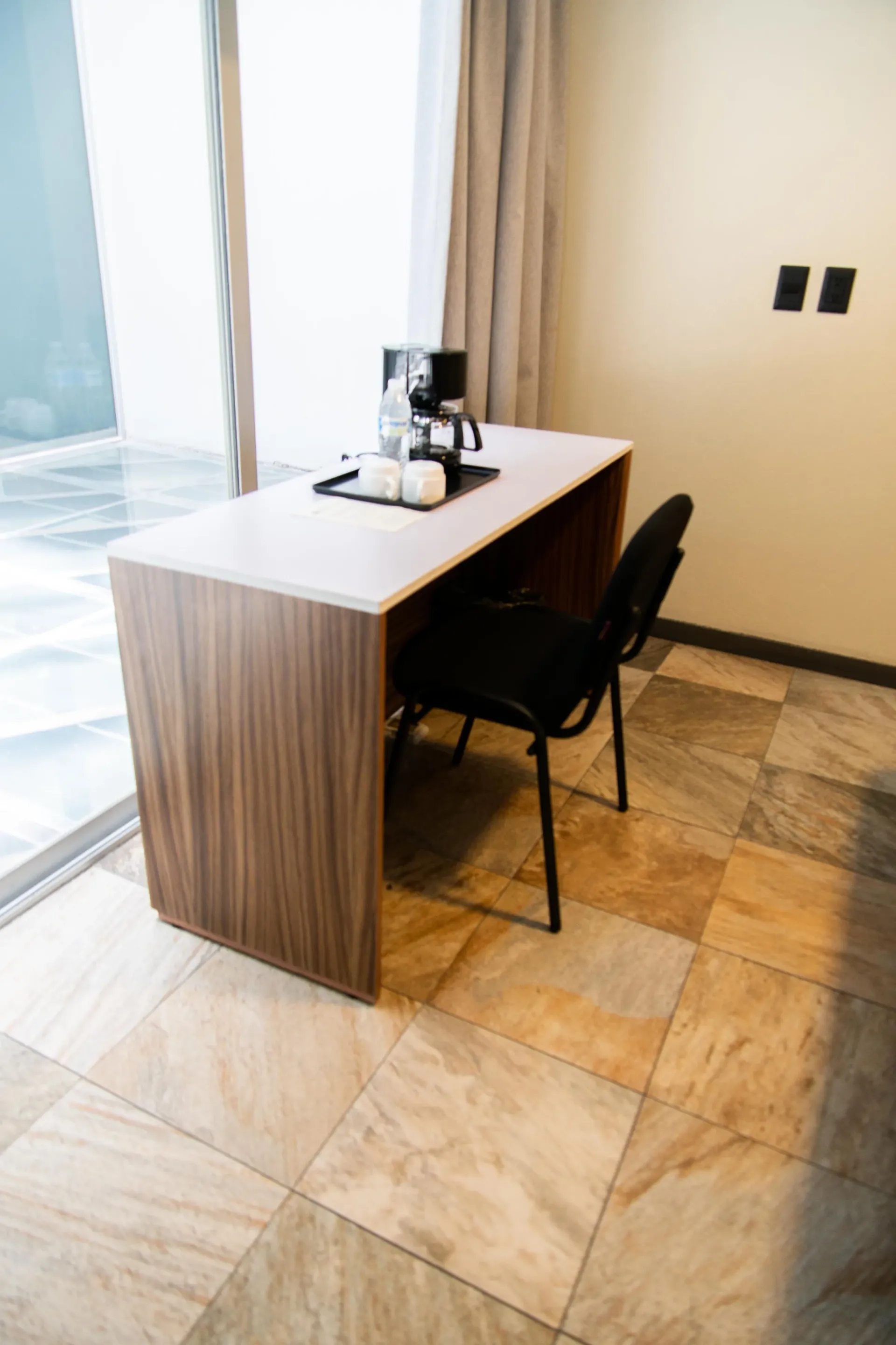 Escritorio y silla minimalistas junto a una ventana luminosa en una habitación alicatada.