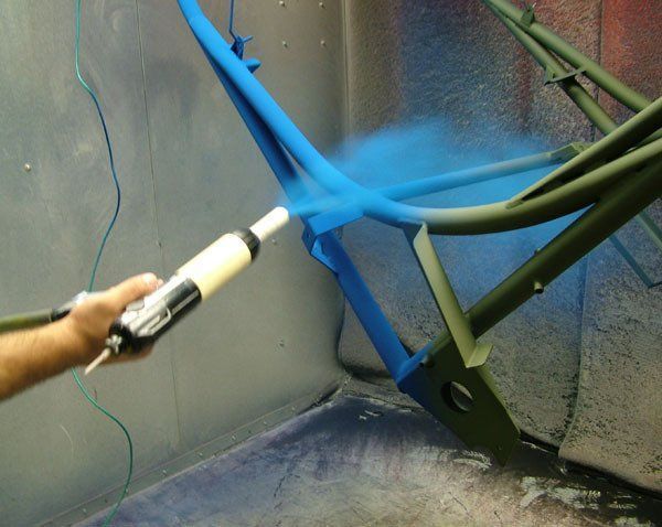 A Person is Spraying Blue Paint on a Piece of Metal