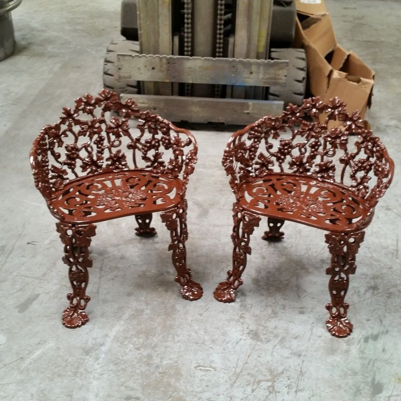 Two Wrought Iron Chairs Are Sitting Next to Each Other in a Warehouse