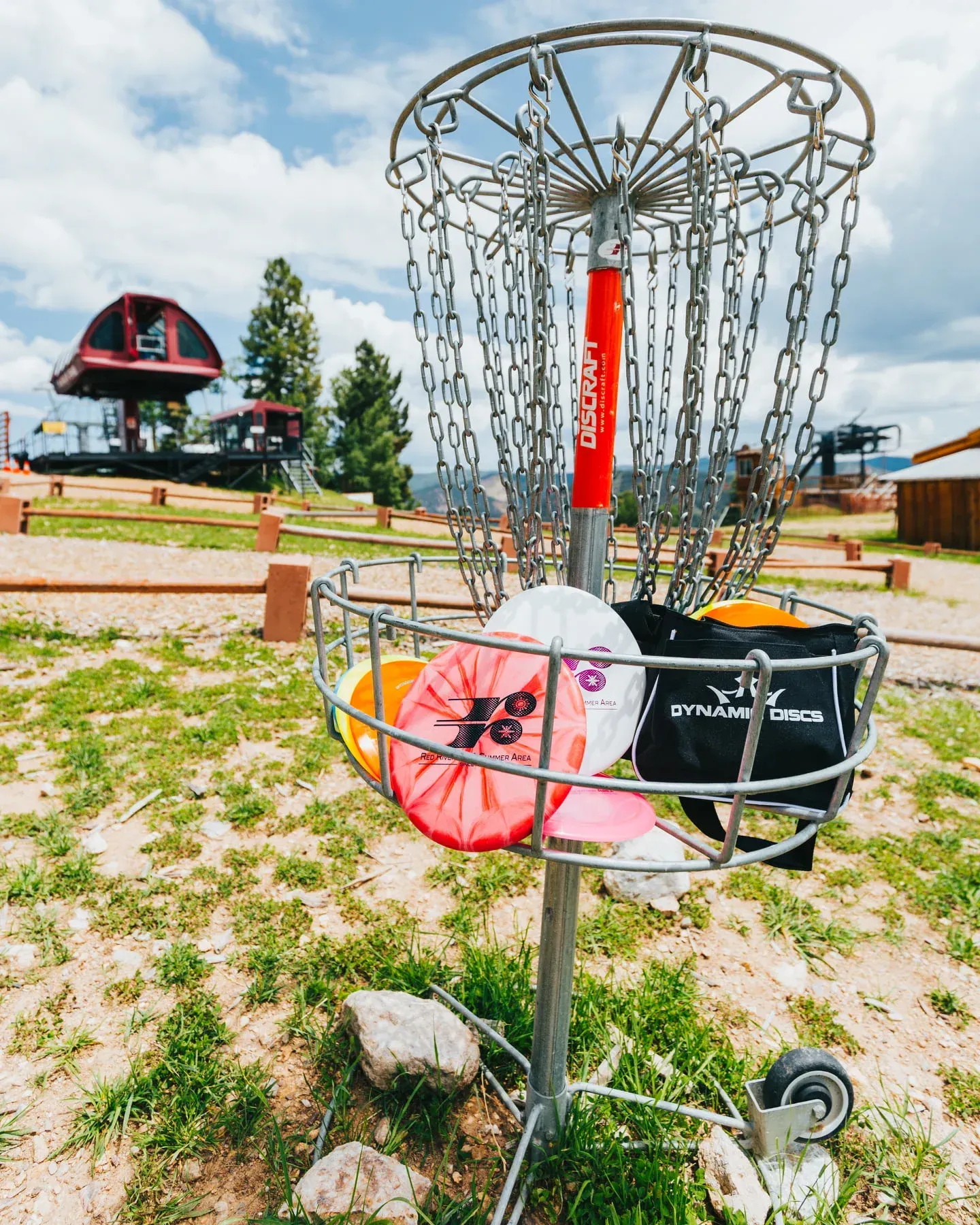 A frisbee golf basket filled with frisbees and a bag.