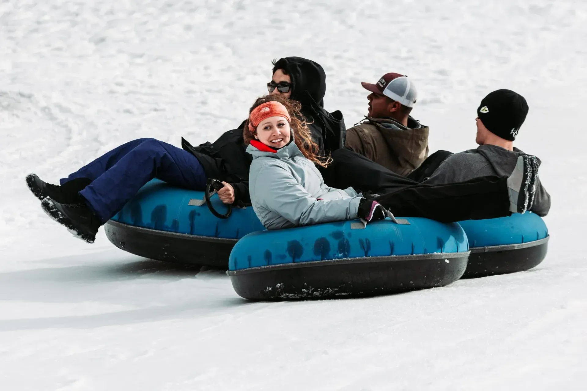 A group of people are riding down a snow covered slope on tubes.