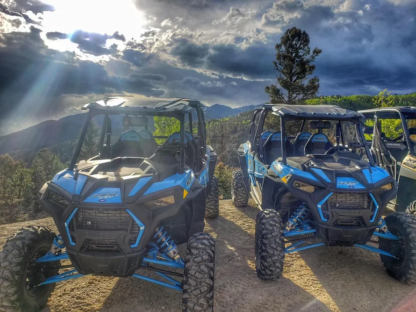 Two atvs are parked next to each other on a dirt road.