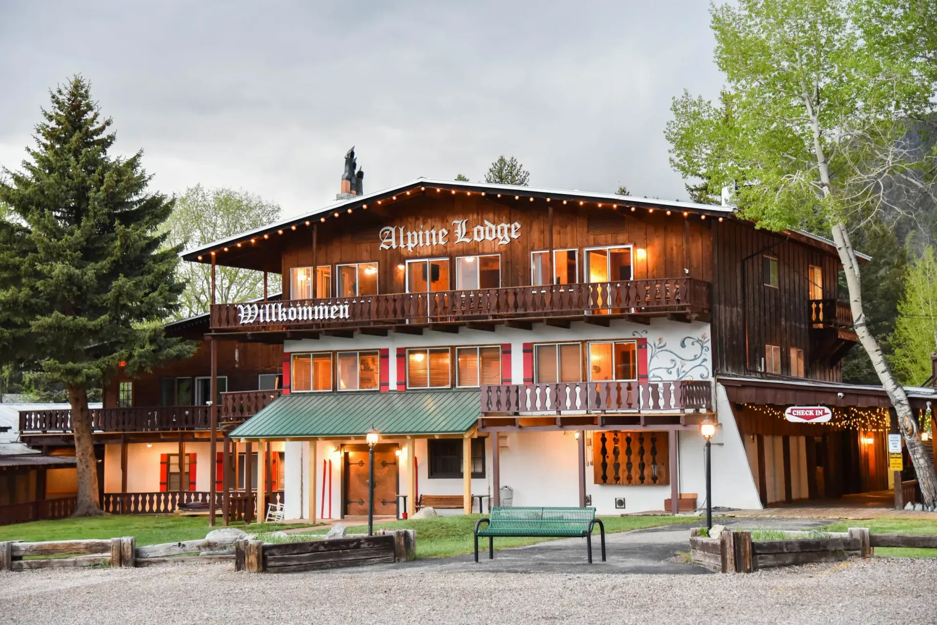 Alpine Lodge, a multi-story building with brown exterior, lit windows, and green accents.
