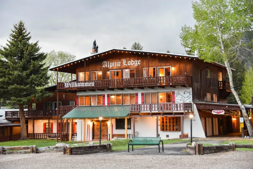 Alpine Lodge, a multi-story building with brown exterior, lit windows, and green accents.