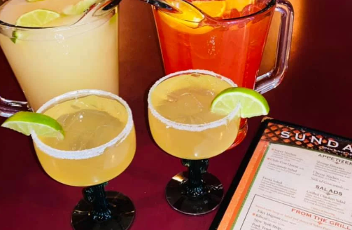Three drinks are on a table next to a menu