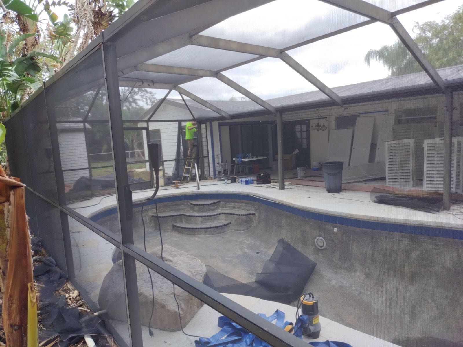 A swimming pool with a screened in area in front of a house.