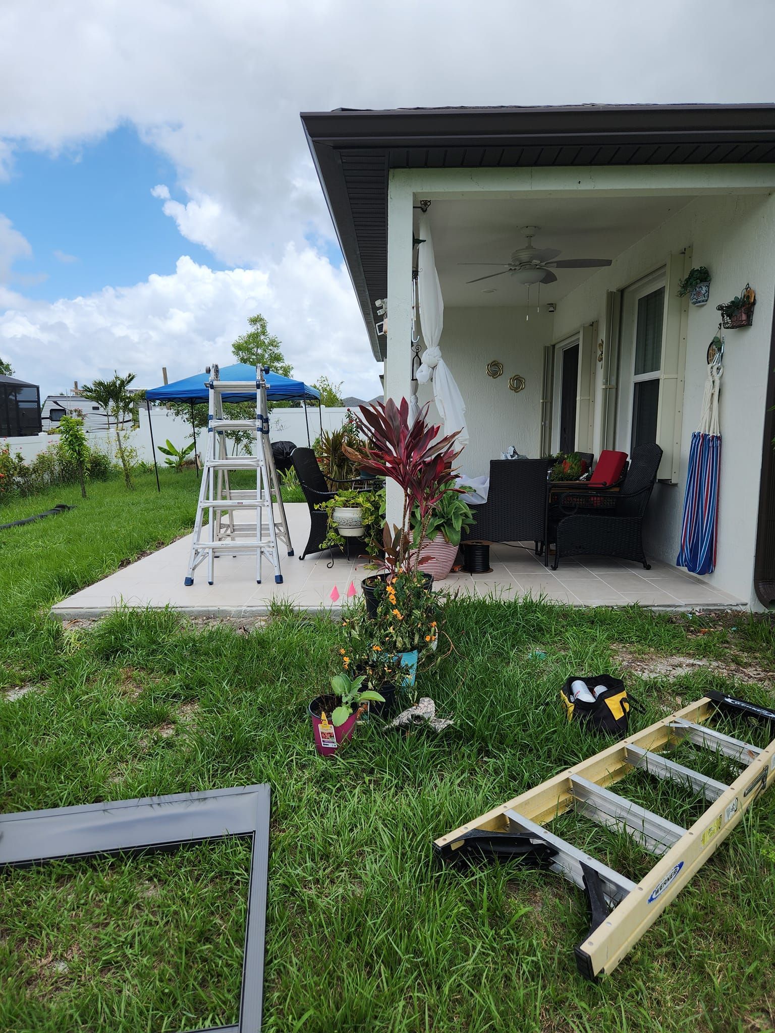 A ladder is sitting in the grass in front of a house.