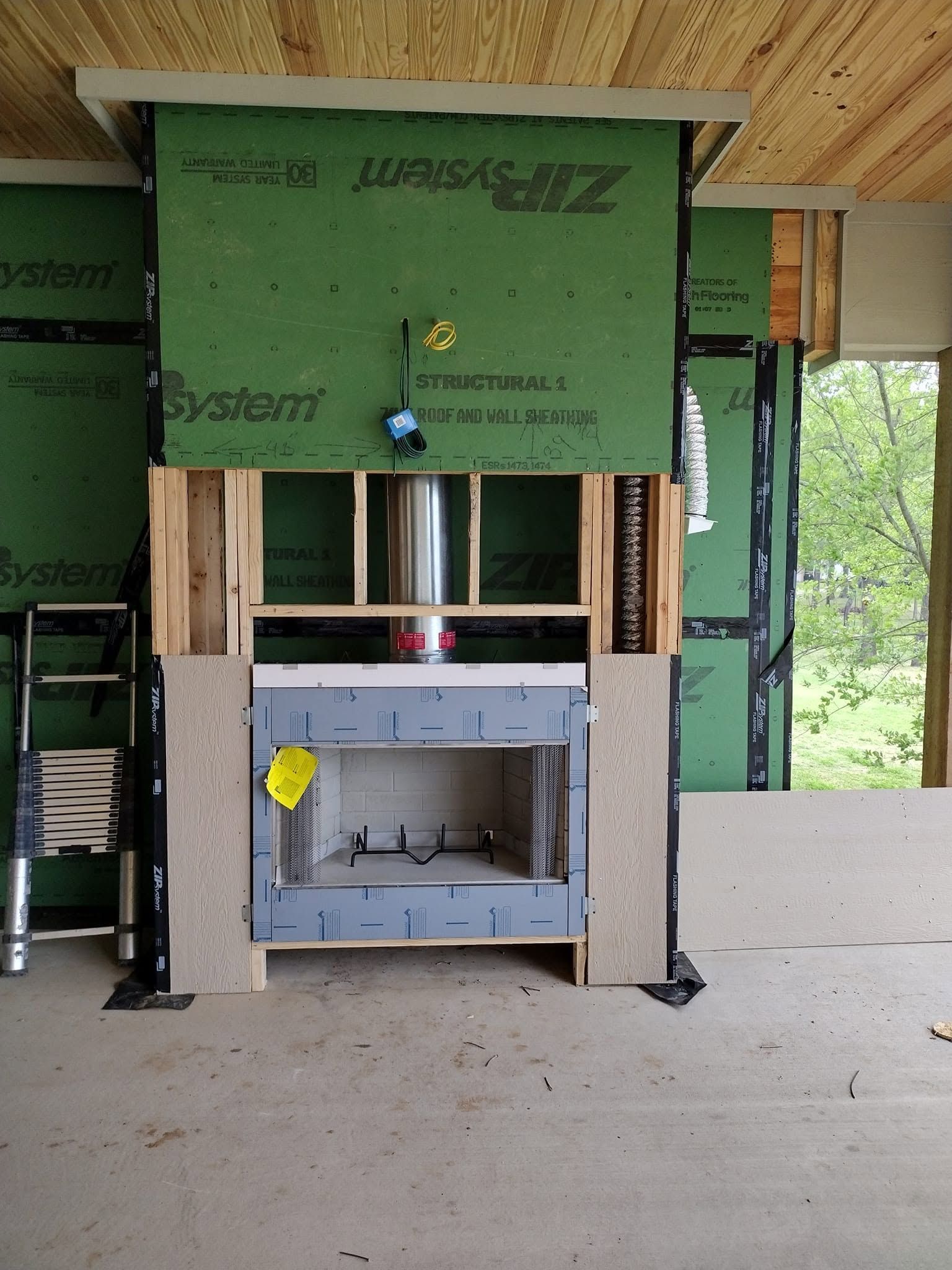 Partially built wall with a sink in a framed house interior, green insulation and open window cutout.