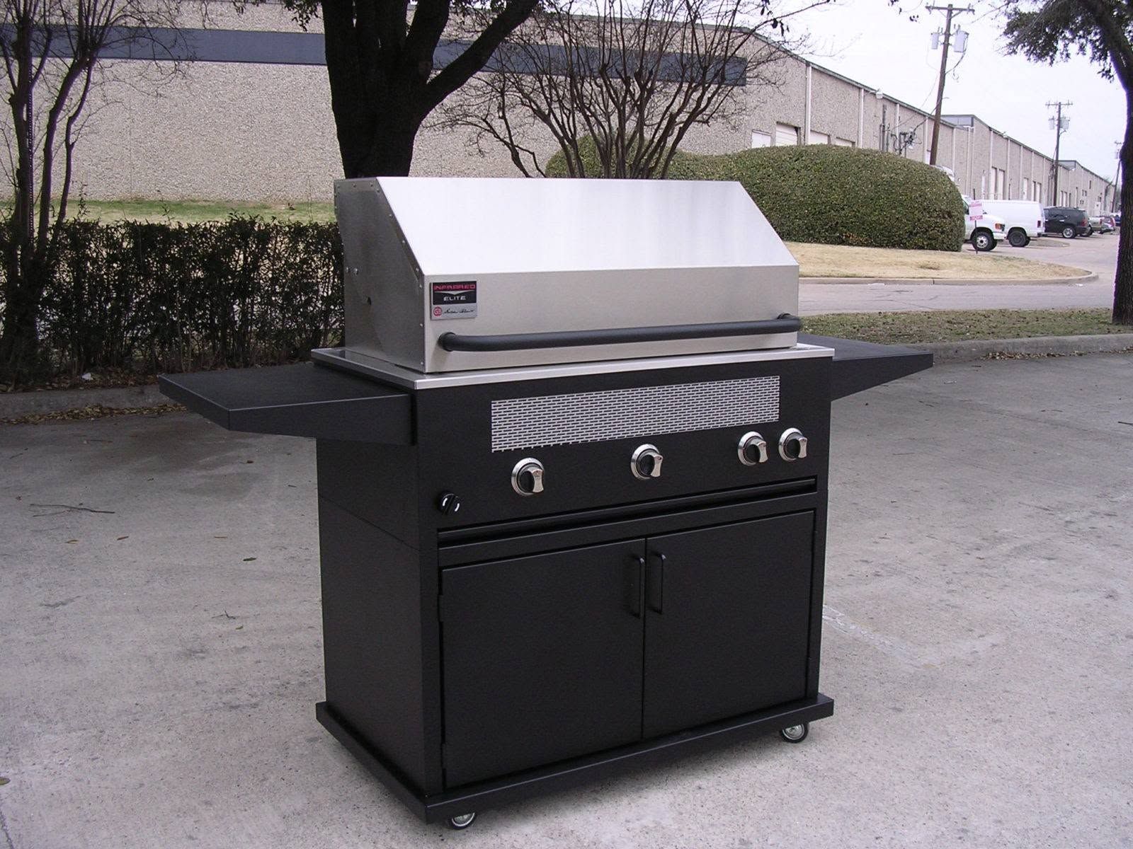 Black outdoor gas grill with stainless steel lid on a paved driveway.