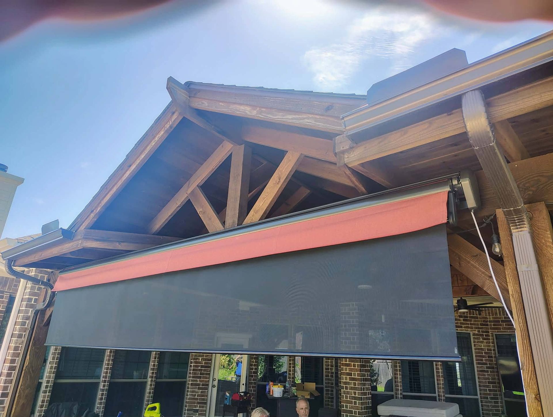 Wooden building with a red awning and dark window shades under a cloudy sky