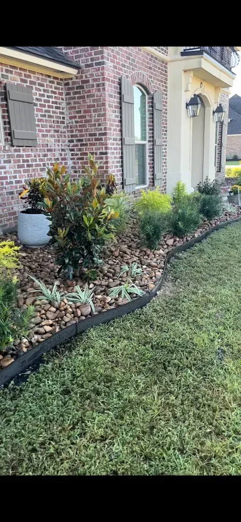 Brick house front yard with curved flower bed, shrubs, and trimmed lawn