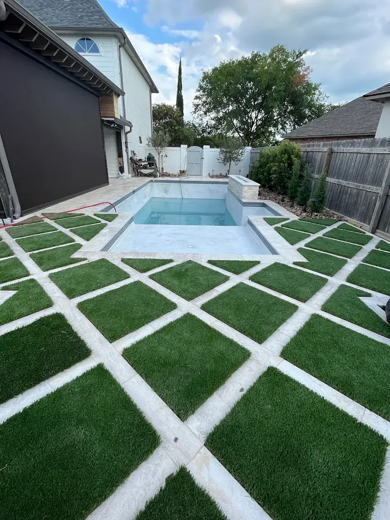 Backyard pool with geometric artificial turf and white stone grid pattern