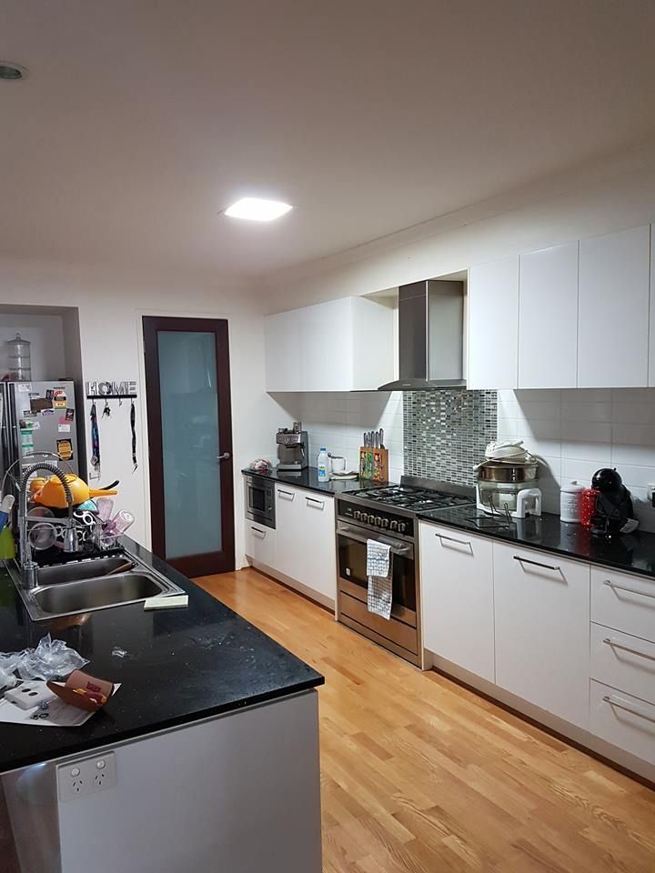 A kitchen with white cabinets , a stove , a sink , and a refrigerator.