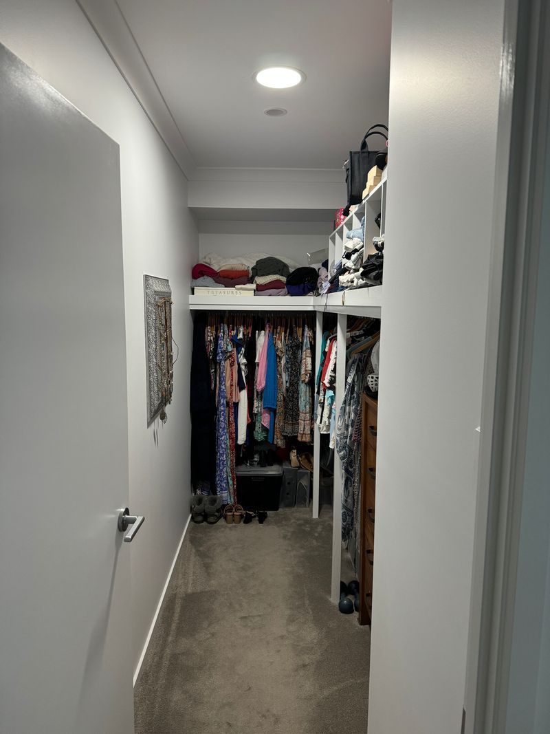 A walk in closet filled with lots of clothes and shoes.