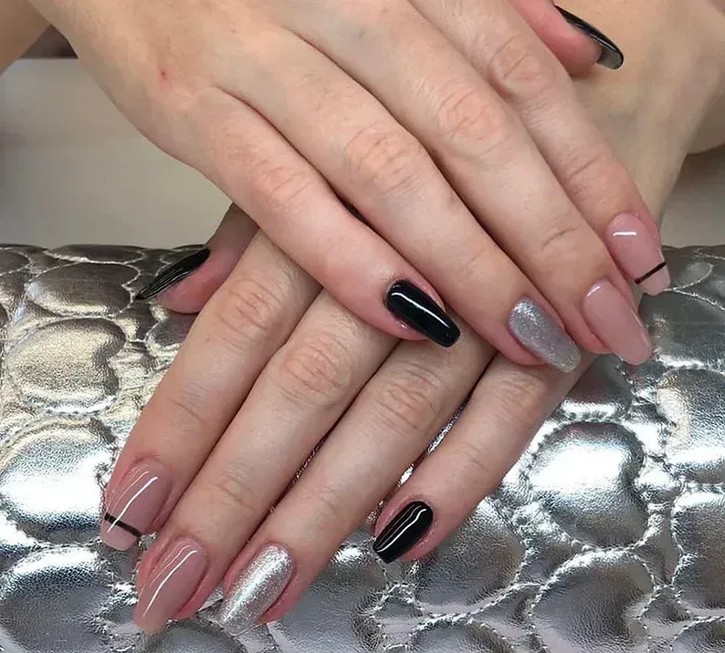 Mani con unghie lunghe a forma di bara. I colori includono nero, argento e color carne, con una sottile striscia nera su alcune.