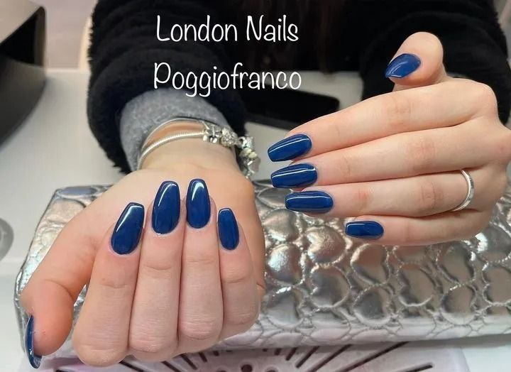 Mani con unghie lucide, blu, a forma di bara. Sopra c'è scritto 